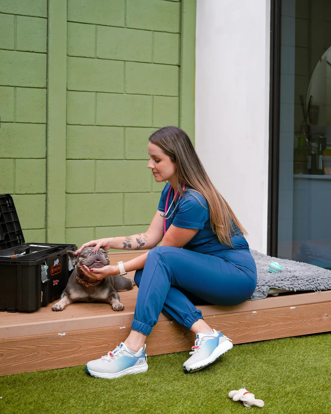 Veterinaria con uniforme azul y zapatos Andrómeda atendiendo a un perro